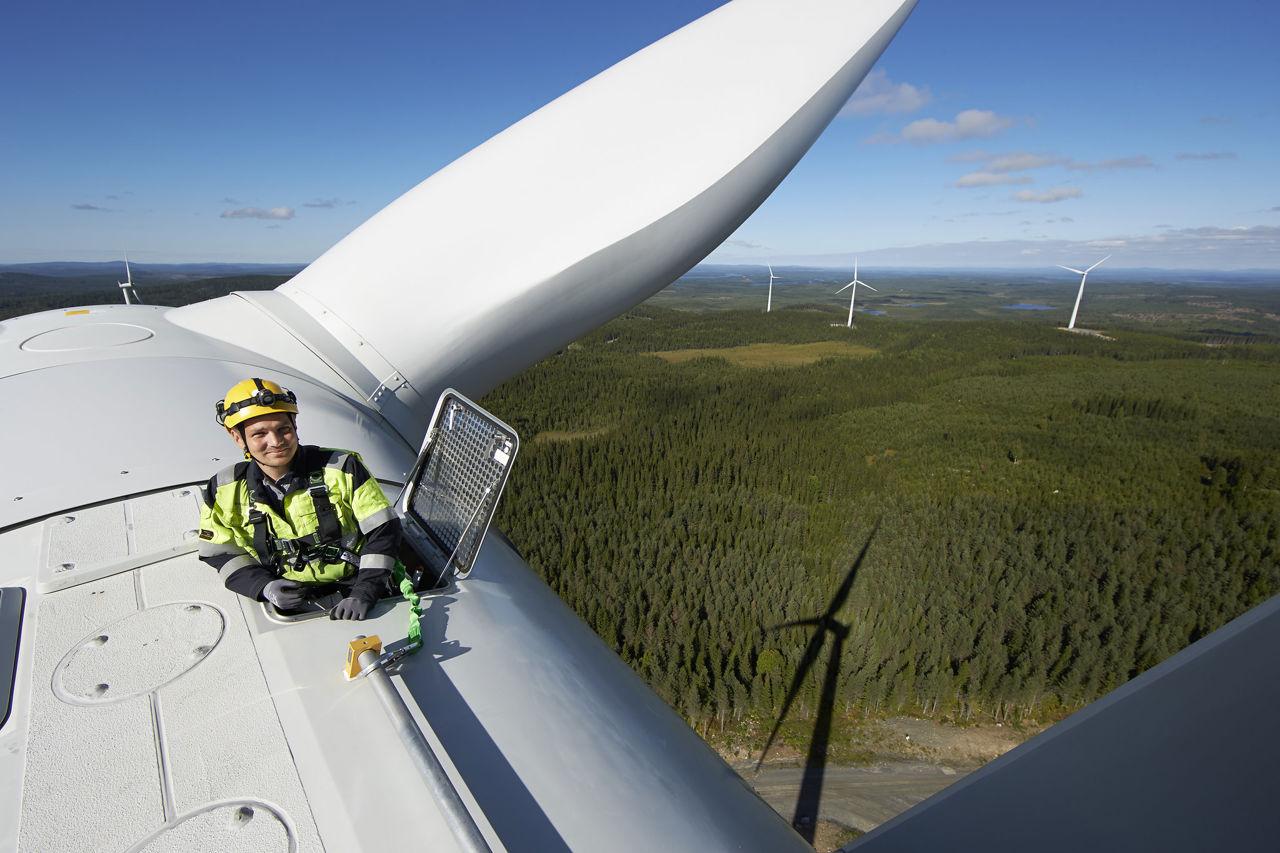 Man standing on top of wind mill